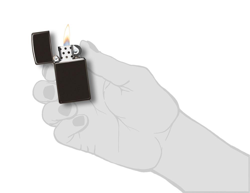 Briquet Zippo Slim High Polish Chrome modèle de base noir, ouvert avec flamme dans une main élégante